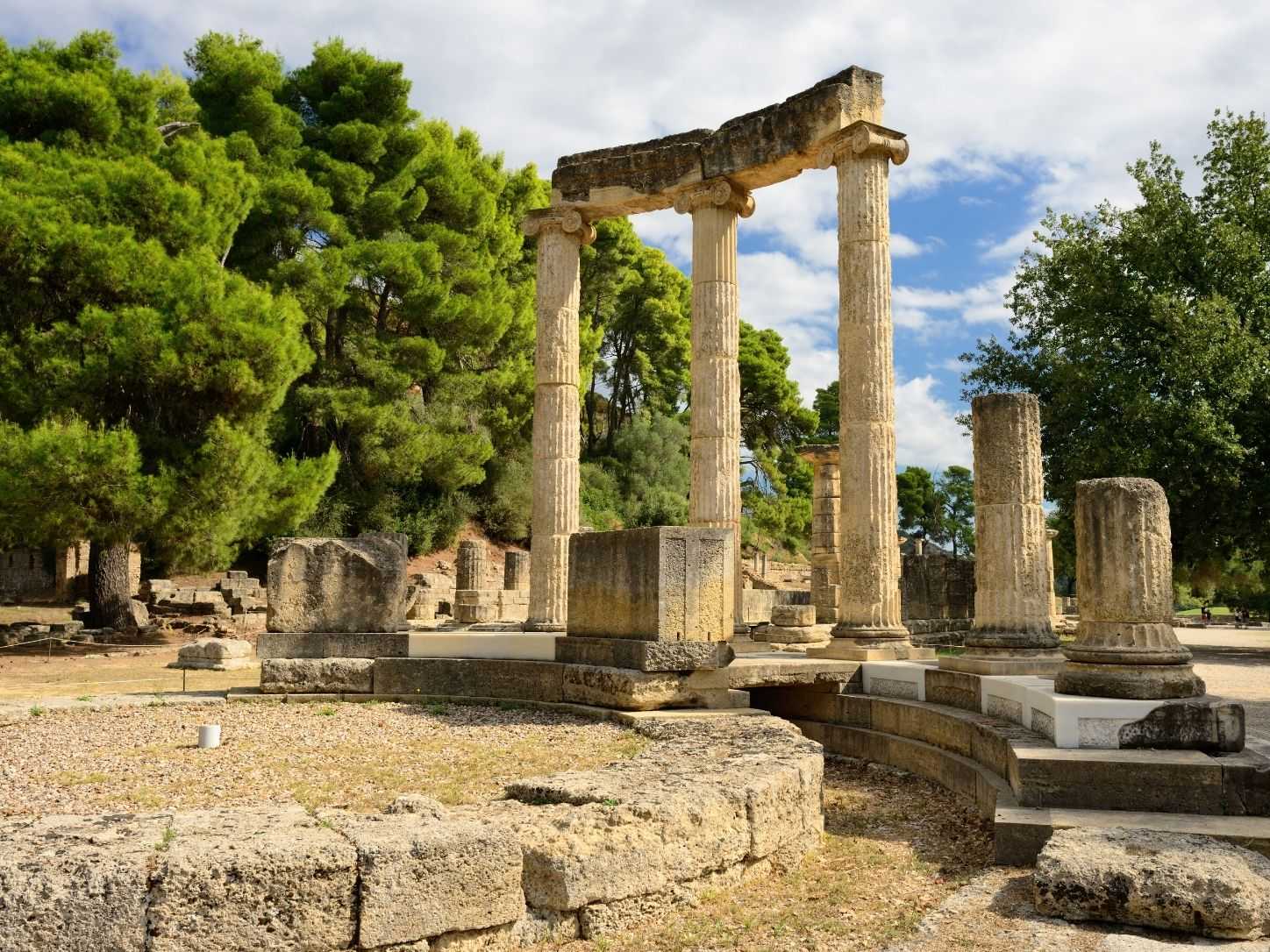 The Ionic columns of the Philippeion at Ancient Olympia, framed by pines