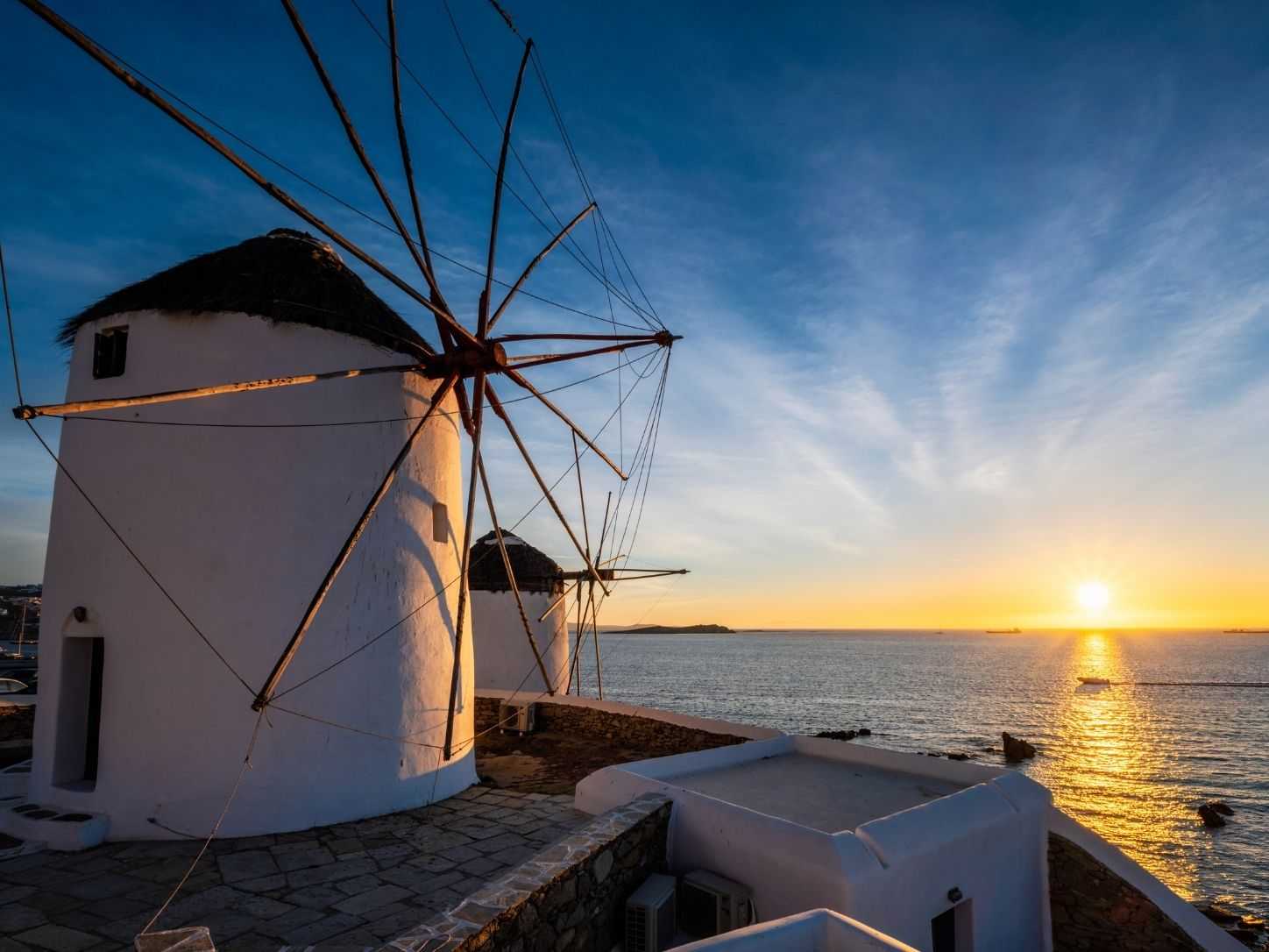 Whitewashed windmills above the sea at Mykonos Town at sunset