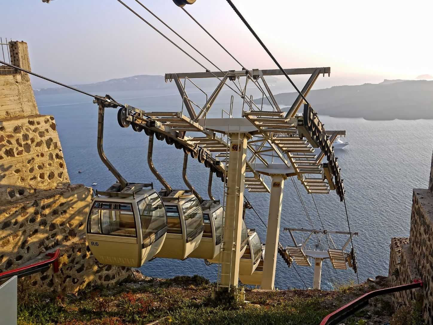 Cable car cabins above the Santorini caldera, a cruise ship anchored below