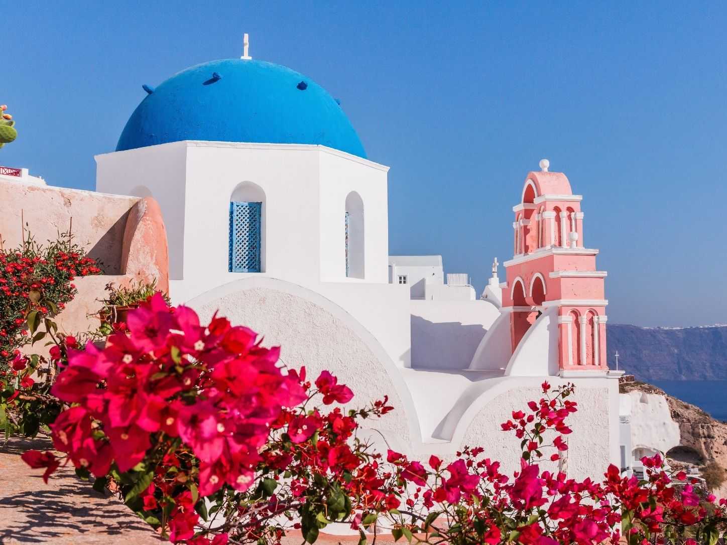 A blue-domed church and bougainvillea in a Santorini village above the caldera